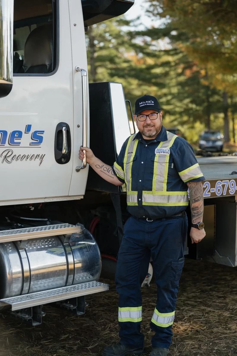 Jason standing at the cab step of a white Milne's flatbed.